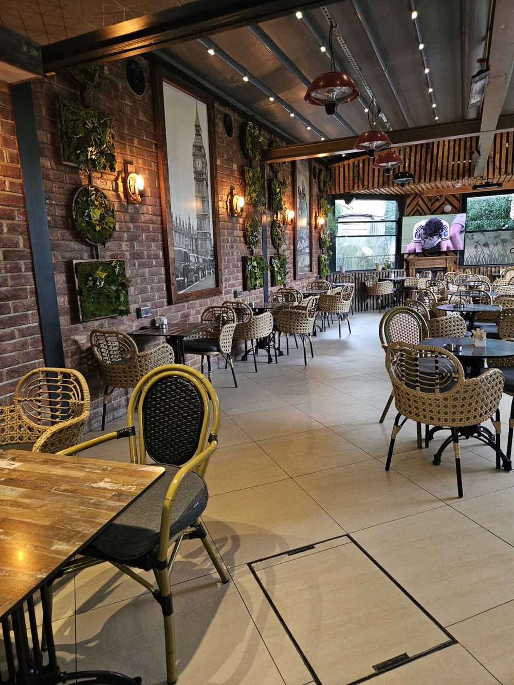 The main dining room, rows of rattan chairs and tables between brick walls and greenery