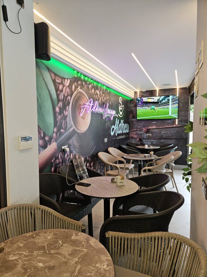 Seating area with a printed coffee-bean mural, marble tables and woven chairs (cropped to exclude lettering)