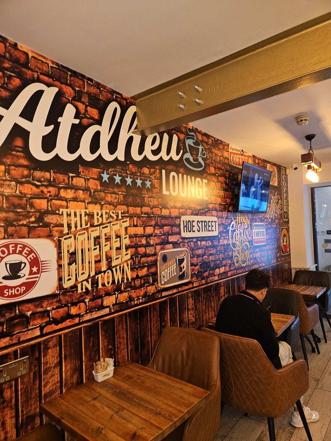 Interior corner with exposed brick, a wooden table and armchairs (cropped to exclude the wordmark)